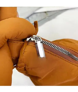 Detail of a smooth silver metal zipper on a brown quilted nylon puffer shoulder bag