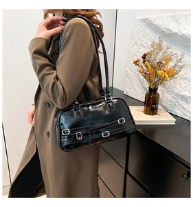 Détail d'un sac à bandoulière en cuir verni noir brillant avec boucles argentées et logo
