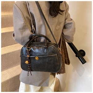 Detail of black retro pillow bag showing textured PU leather and golden charm