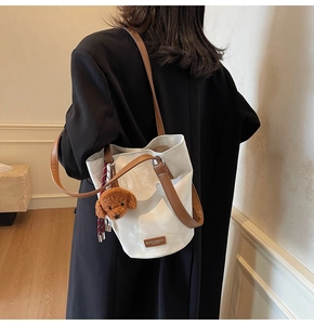 White vintage bucket bag with brown straps and cute bear charm shown on model shoulder