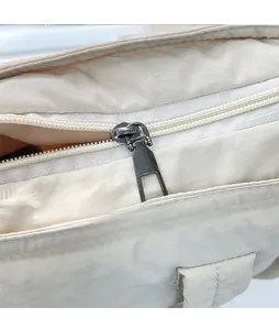 Detailaufnahme eines glatten Metallreißverschlusses an einer beigen Nylon-Einkaufstasche