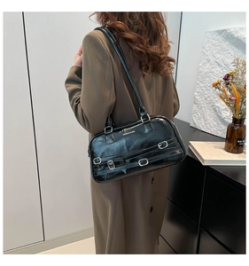 Détail du sac bandoulière noir brillant avec trois boucles argentées porté par un modèle