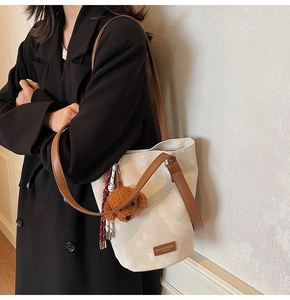 Detail of cream bucket bag with brown leather straps and cute plush dog pendant