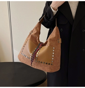 Detail of tan tote bag featuring silver hexagonal rivets and woven tassel accents