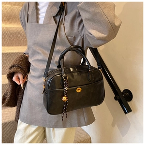 Detail of black retro pillow bag with golden lock and charm on a staircase