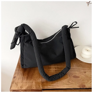 Detail of black quilted puffer bag showing smooth nylon fabric and silver zipper