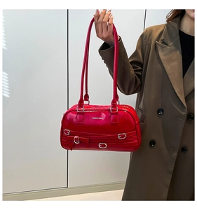 Détail du sac à bandoulière en cuir rouge brillant avec boucles et nœud décoratif
