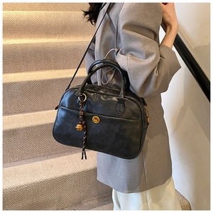 Detail view of black vintage leather Boston bag with gold twist lock and tassel decoration