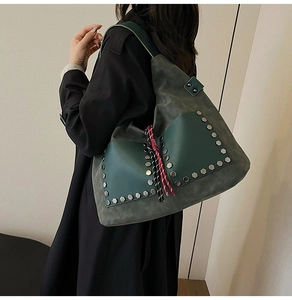 Detail of dark green tote bag with silver studs and tricolor woven tassel decor
