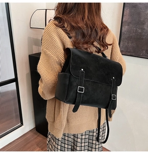 Detalle de la mochila negra mate con hebillas plateadas y cierre de solapa texturizada