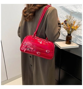Détail du sac bandoulière en cuir verni rouge avec boucles argentées et nœud décoratif