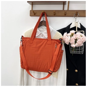 Detail der orangefarbenen gesteppten Nylontasche mit Reißverschluss und Schultergurt