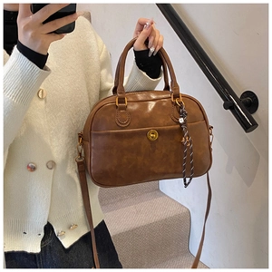 Detail of brown vintage Boston bag with gold hardware and woven rope accessory