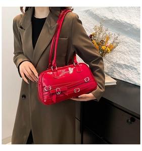Détail d'un sac d'épaule rouge brillant avec boucles argentées et nœud décoratif chic