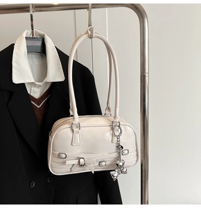 Détail du sac à bandoulière blanc crème avec nœuds chics et breloques en métal argenté
