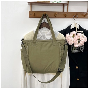 Detail der armee-grünen gesteppten Puffer-Tasche mit verstellbarem Riemen und geräumigen Taschen