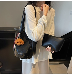 Detail of black faux leather tote bag set including a small pouch and teddy charm accessory
