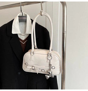 Détail du sac à épaule crème en similicuir avec nœuds décoratifs et charms en cœur