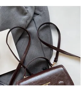 Macro detail of dark brown retro wrinkled PU leather bag with golden fashion text and strap