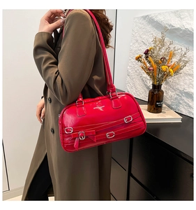 Détail du sac bandoulière en cuir verni rouge avec boucles argentées et nœud décoratif