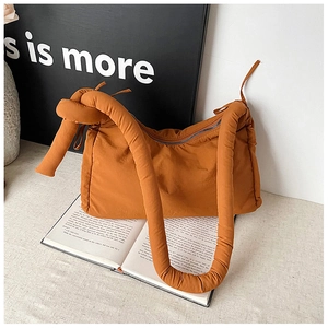 Detailed macro view of an orange padded nylon crossbody bag with a knot handle design