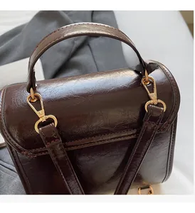 Detail of brown oil wax leather texture with shiny gold hardware on this chic crossbody bag