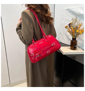 Détail du sac à bandoulière en cuir verni rouge avec boucles argentées et nœud élégant