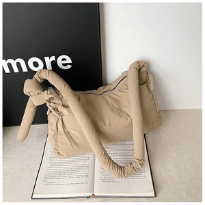 Detail of khaki quilted puffer tote bag featuring a knotted handle on minimalist books