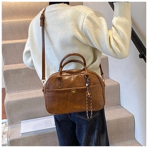 Close-up of brown vintage leather Boston bag with metal lock and woven strap detail