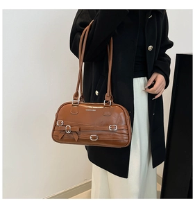 Détail du sac à bandoulière en cuir marron avec boucles argentées et nœud décoratif
