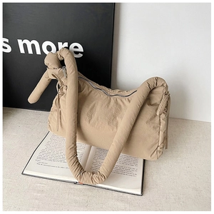 Detail of beige puffer nylon bag featuring a thick padded shoulder strap with knot