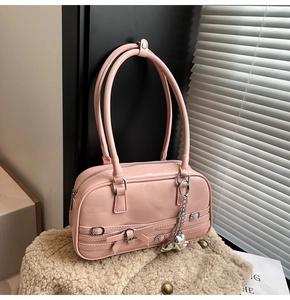 Détail du sac à main en cuir PU rose avec breloque cœur et nœud sur fond texturé doux