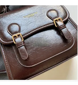 Detail of retro dark brown leather messenger bag with gold buckles and fashion logo