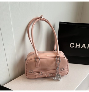 Détail d'un sac à bandoulière rose Y2K avec breloques métalliques et nœud décoratif