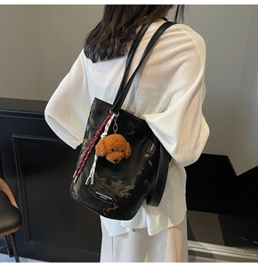 Detail of black marble pattern tote bag with teddy dog pendant and woven tassel