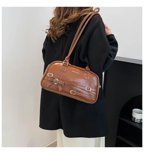 Vue détaillée du sac Boston en cuir marron avec nœuds porté sur un manteau foncé