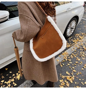 Brown leather crossbody bag with white faux fur trim shown in a warm autumn street setting