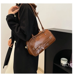 Détail de sac bandoulière en cuir PU marron avec boucles argentées vintage et finitions métal