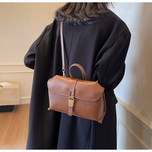 Detailed view of a vintage brown leather crossbody bag with gold metal buckle hardware