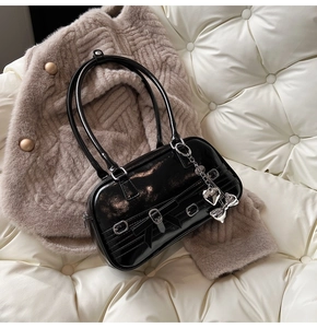 Gros plan sur le sac à bandoulière en cuir verni noir avec charms en forme de cœur