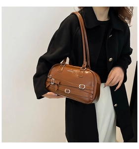 Détail d'un sac porté épaule en cuir huilé marron avec nœud décoratif et boucle