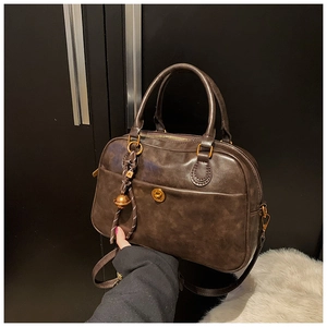 Detailed view of coffee brown retro Boston bag with gold twist lock and bell charm