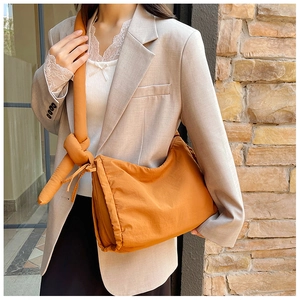 Fashionable orange padded nylon crossbody bag with stylish knot strap detail for women