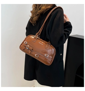 Détail d'un sac à bandoulière en similicuir marron avec boucles argentées et décoration nœud