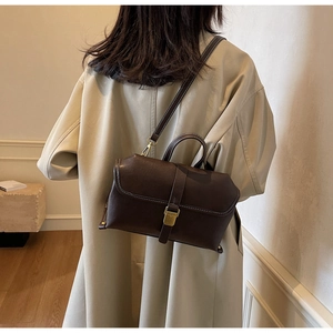 Detail of dark brown vintage leather crossbody bag with contrast stitching and metal buckle