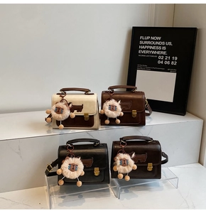 Detail of four retro flap bags in beige, brown, and black with cute animal charms