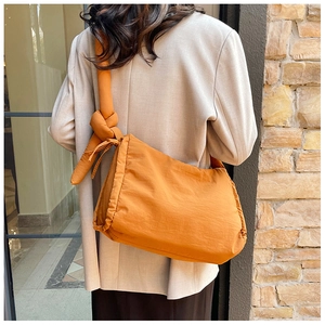 Detailed back view of a mustard yellow quilted nylon shoulder bag with knot strap detail