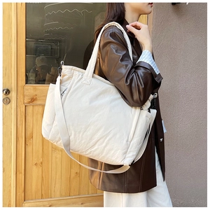Detailansicht der cremefarbenen Stepptasche aus Nylon mit breitem Gurt und weicher Haptik