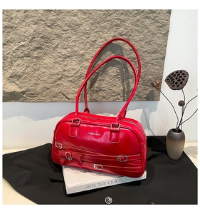 Détail d'un sac à bandoulière en cuir rouge avec boucles argentées et nœud décoratif