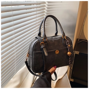 Detail of grey retro Boston bag showing matte texture, bronze hardware, and bell charm